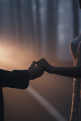 Intimate moment of the couple holding hands, framed by soft shadows.