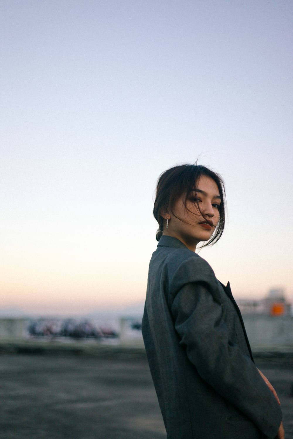 woman in gray coat standing near body of water during daytime