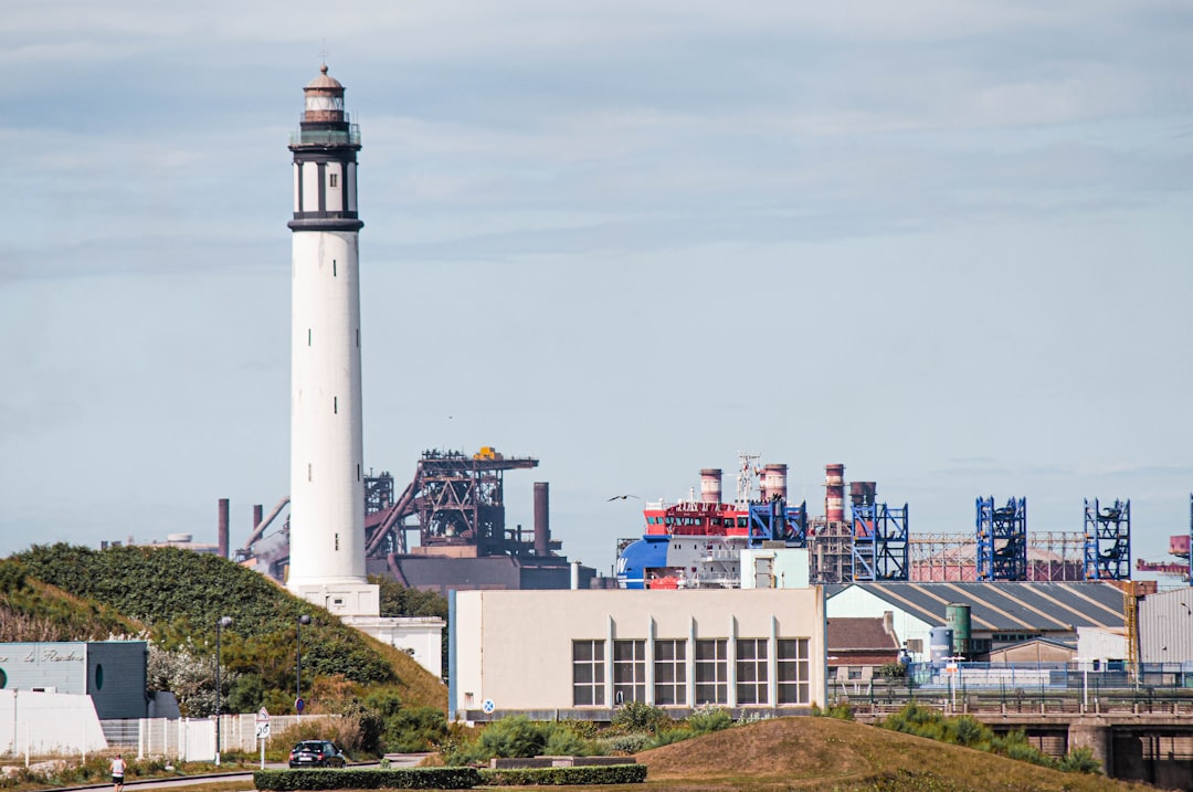 white and black lighthouse near city buildings during daytime