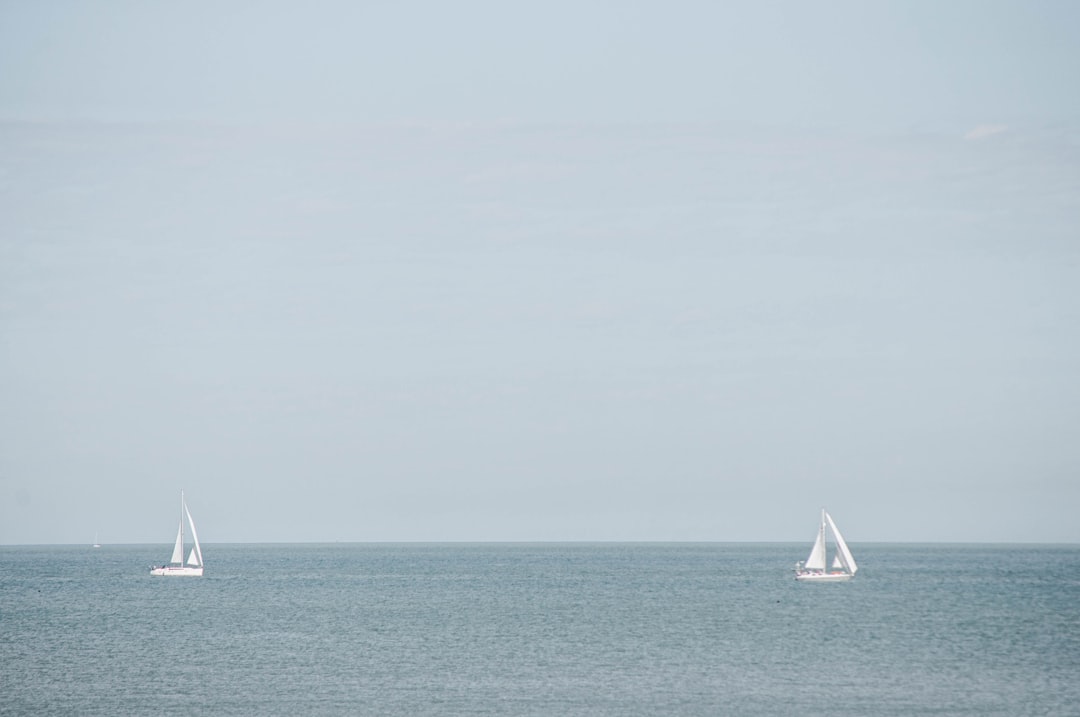white sailboat on sea under white sky during daytime