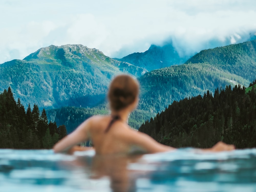 topless boy in water near green trees during daytime