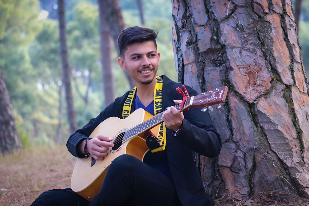 man in black and red polo shirt playing brown acoustic guitar