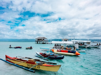 yellow and red boats on sea under white clouds and blue sky during daytime