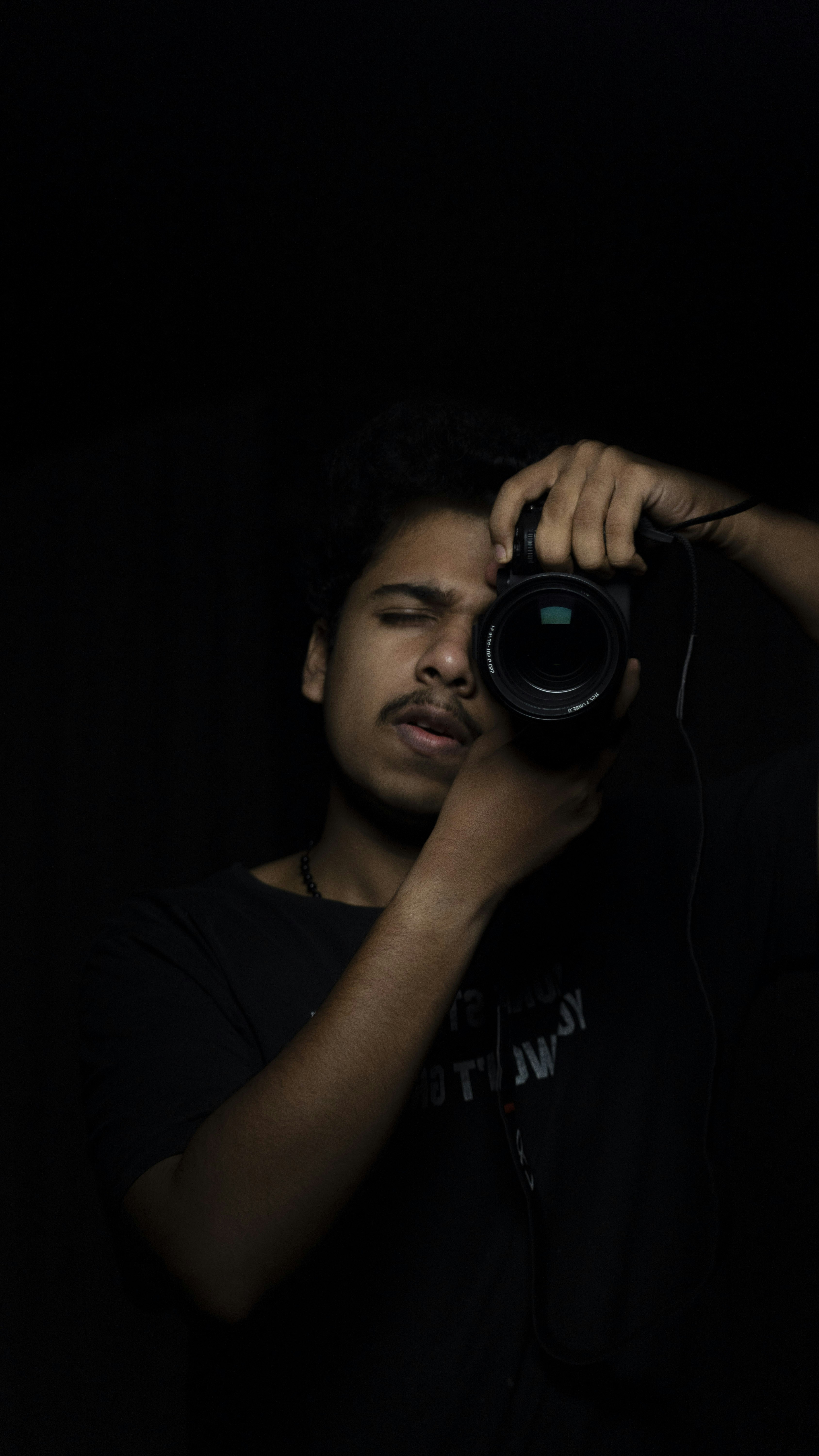 man in black crew neck t-shirt holding black camera