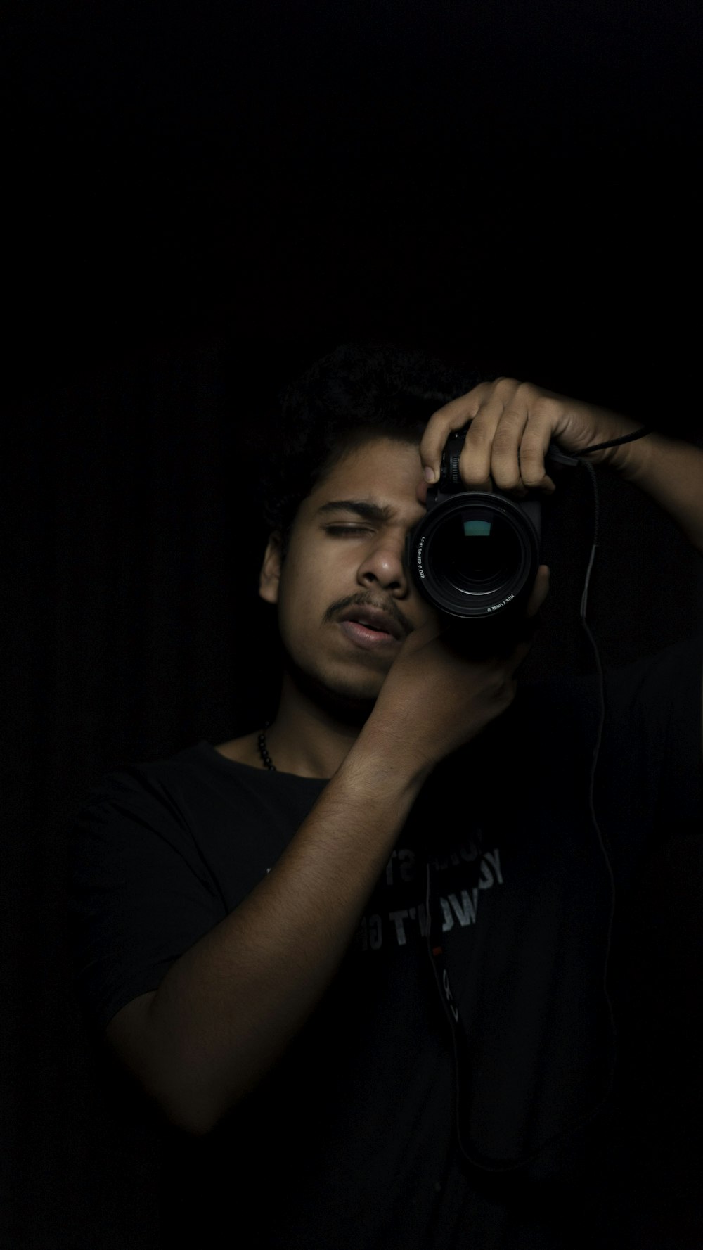 man in black crew neck t-shirt holding black camera