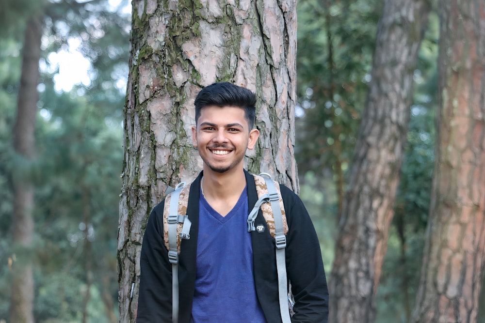 man in blue and white polo shirt standing beside tree