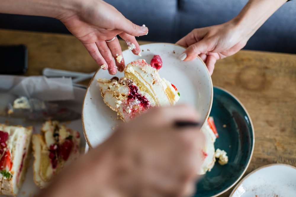 person holding white ceramic bowl with white and red cream