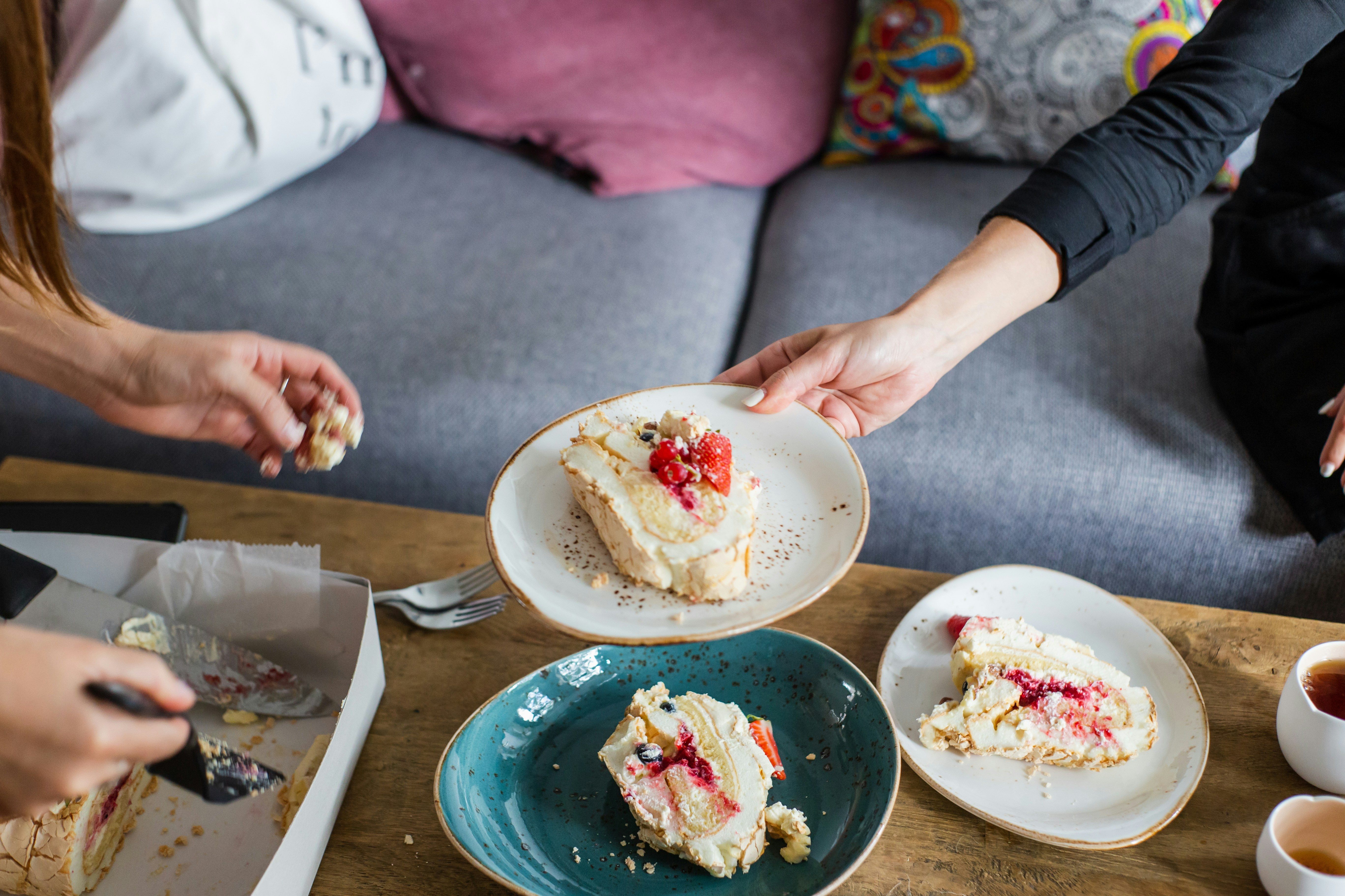 Friends reaching for slices of cake on a coffee table