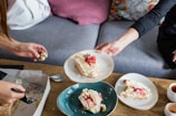A close-up of hands sharing a slice of cake and a salgadinho at a festive table.