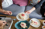 A smiling person holding a tray of assorted homemade cakes ready to share