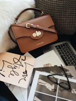 Elegant office handbag in warm nude shade placed beside a sleek laptop and coffee cup.