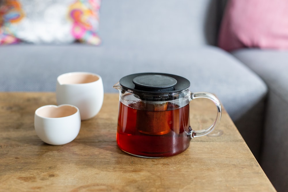 Taza de cerámica blanca junto a taza de vidrio transparente sobre mesa de madera marrón