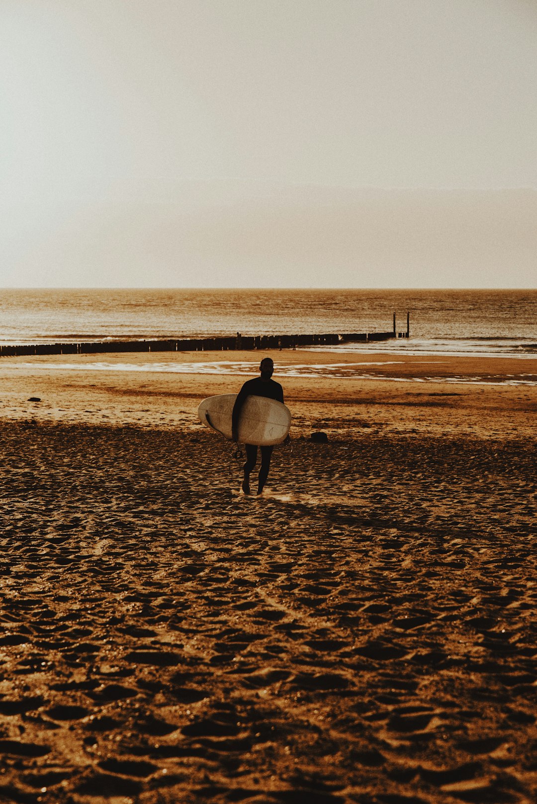 person in white shirt walking on brown sand during daytime