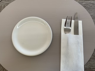 A neatly arranged set of polished catering utensils on a white tablecloth.