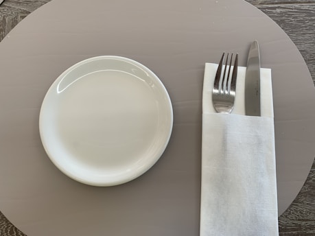 A neatly arranged set of polished catering utensils on a white tablecloth.
