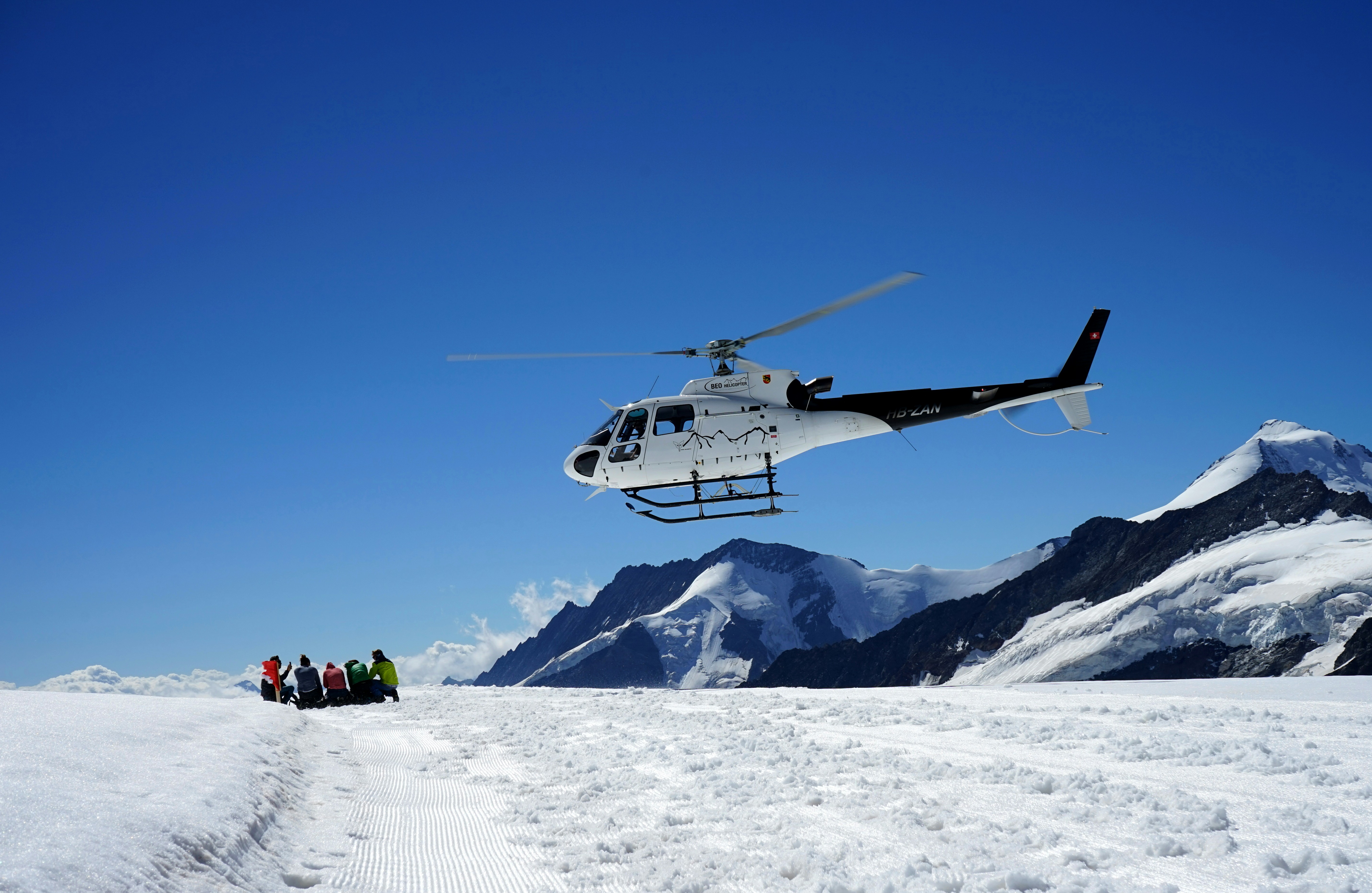 Dron blanco y negro volando sobre una montaña cubierta de nieve durante el día