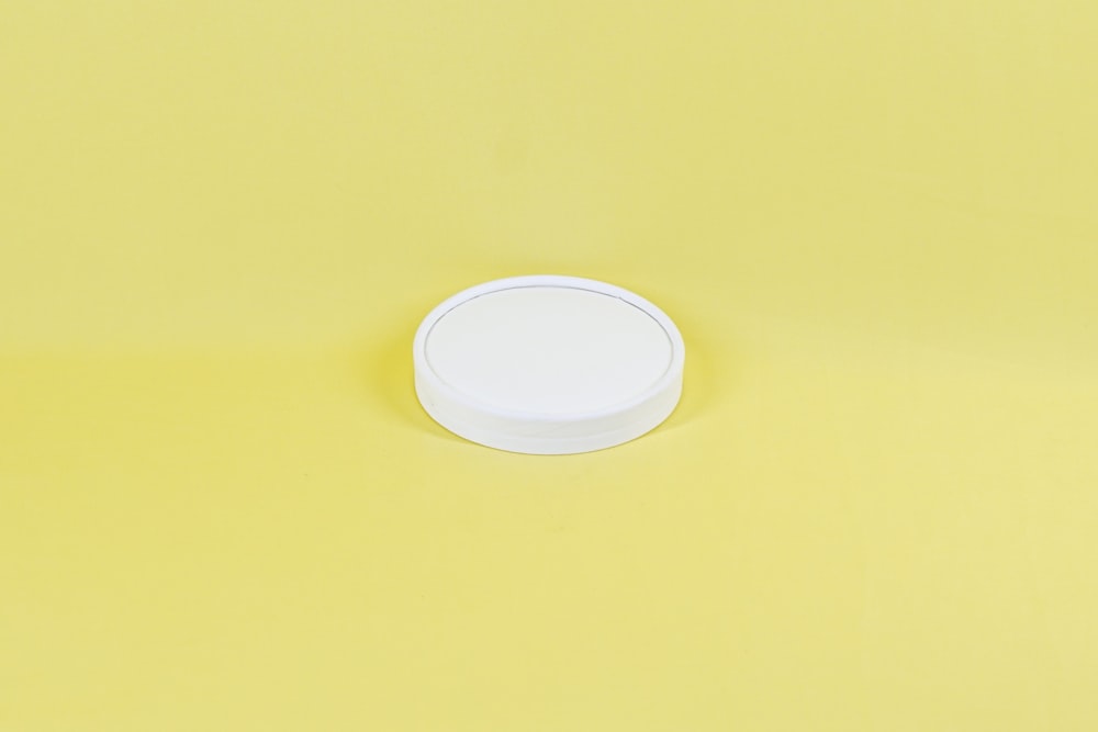 white round plastic container on yellow surface