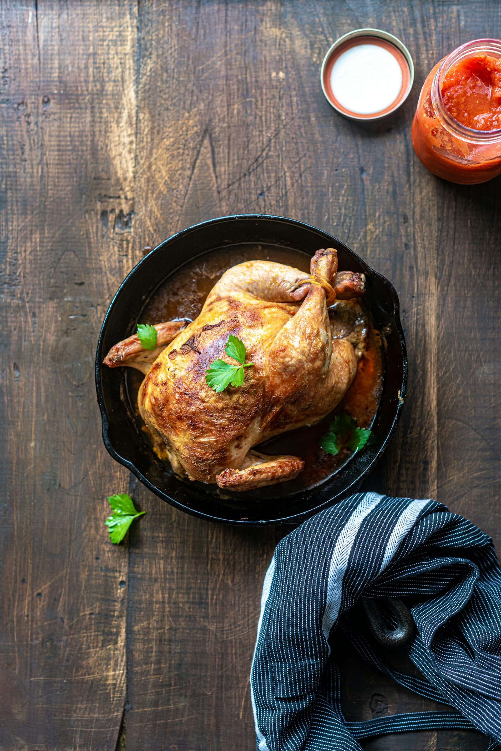 Poulet entier rôti dans une poêle en fonte, vu de dessus sur une table en bois