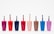 Eight nail polish bottles in various bright colors are arranged in a row against a plain white background. The bottles feature shades including pink, red, dark blue, light orange, brown, light blue, and purple. Each bottle has a visible brush sticking out, showcasing the precise design typical for nail polish containers.