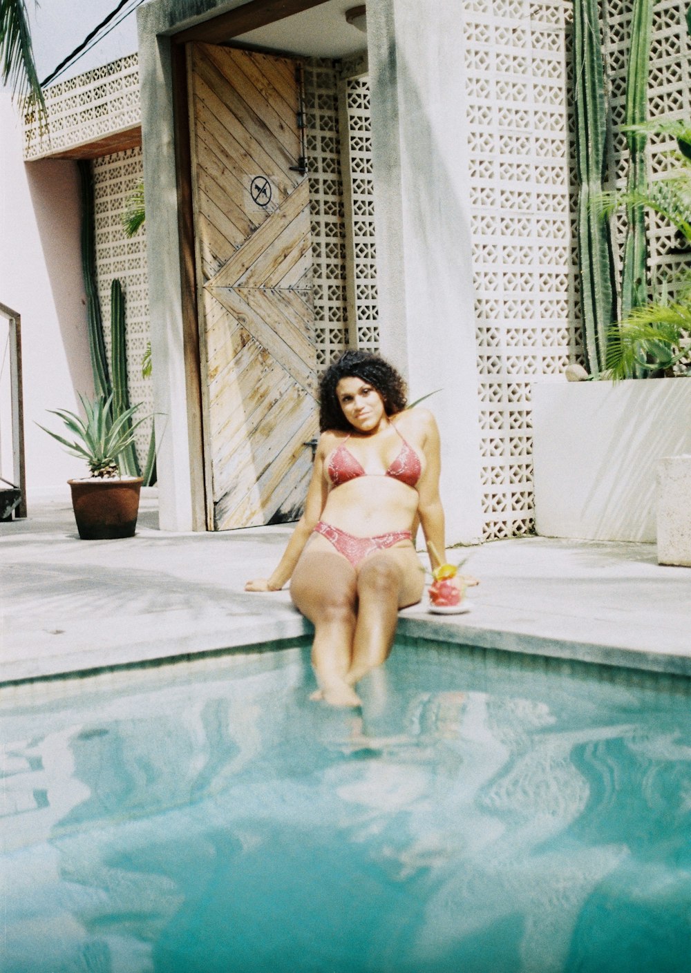 woman in pink bikini sitting on swimming pool during daytime