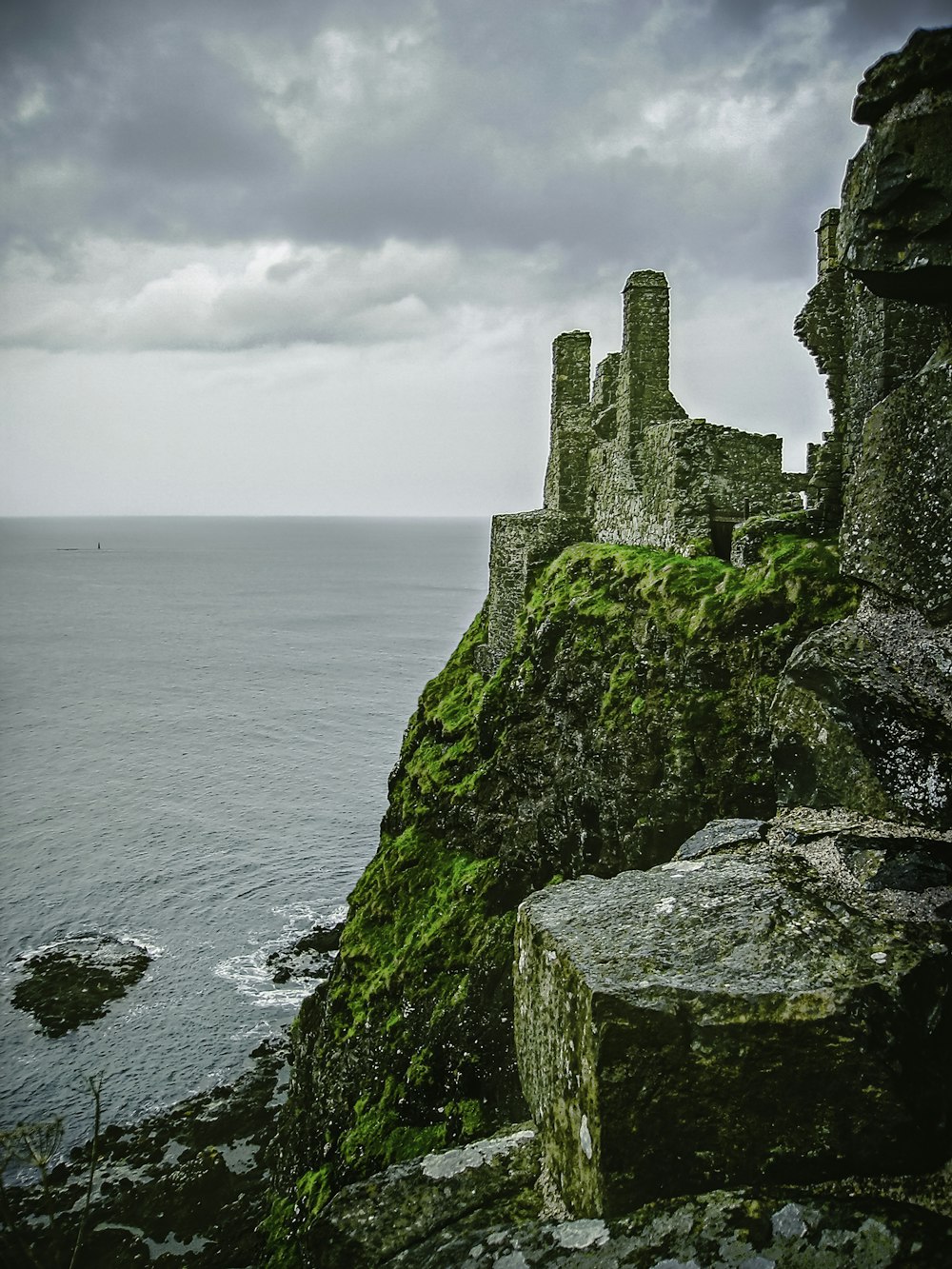 gray concrete castle on cliff by the sea under white clouds during daytime