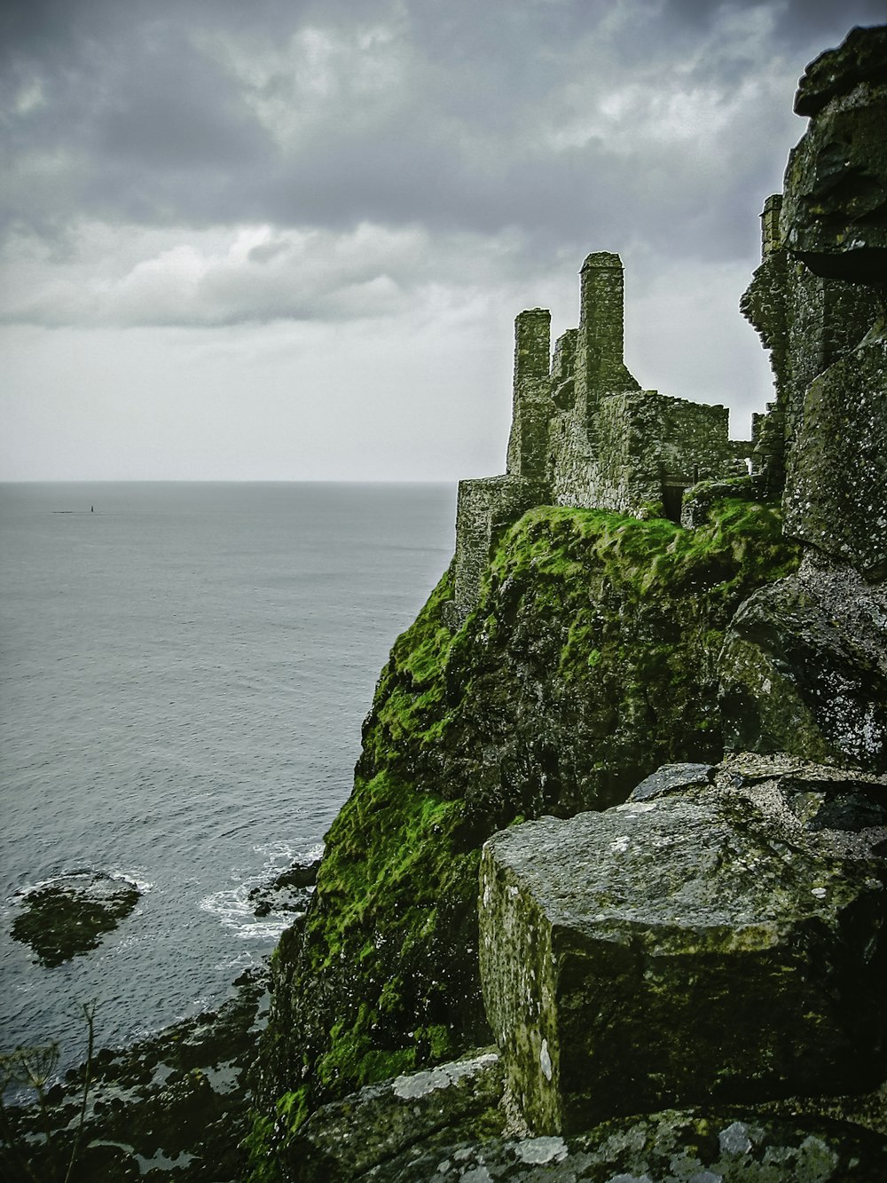 Castillo de hormigón gris en el acantilado junto al mar bajo nubes blancas durante el día