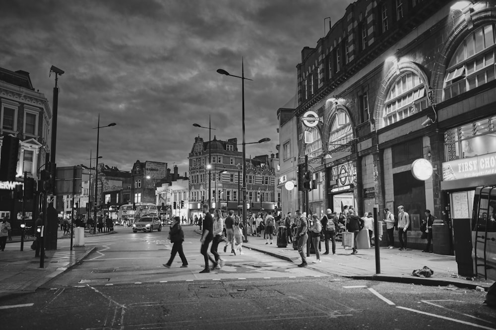 grayscale photo of people walking on street near building