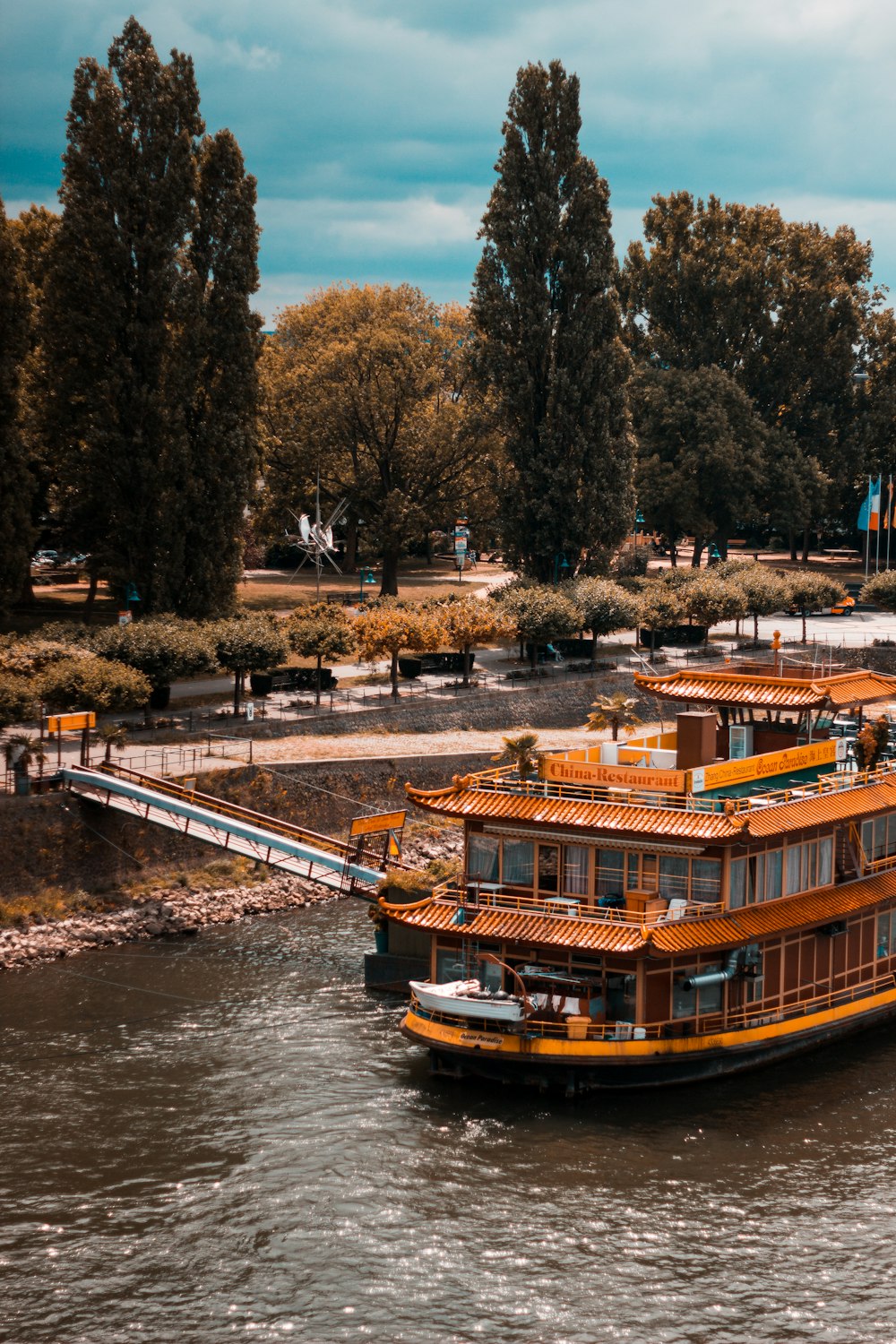 日中の川に浮かぶ茶色と白のボート