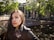 A smiling young woman holding her approved visa document with a backdrop of Amsterdam canals.