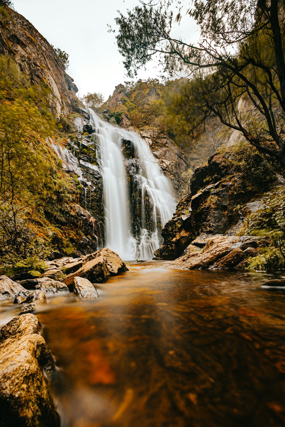 water falls between brown and green rocks