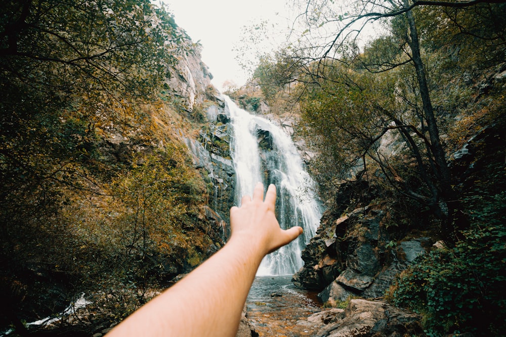 persons left foot on brown rock near waterfalls during daytime