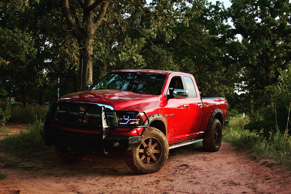 red chevrolet single cab pickup truck parked beside green tree during daytime