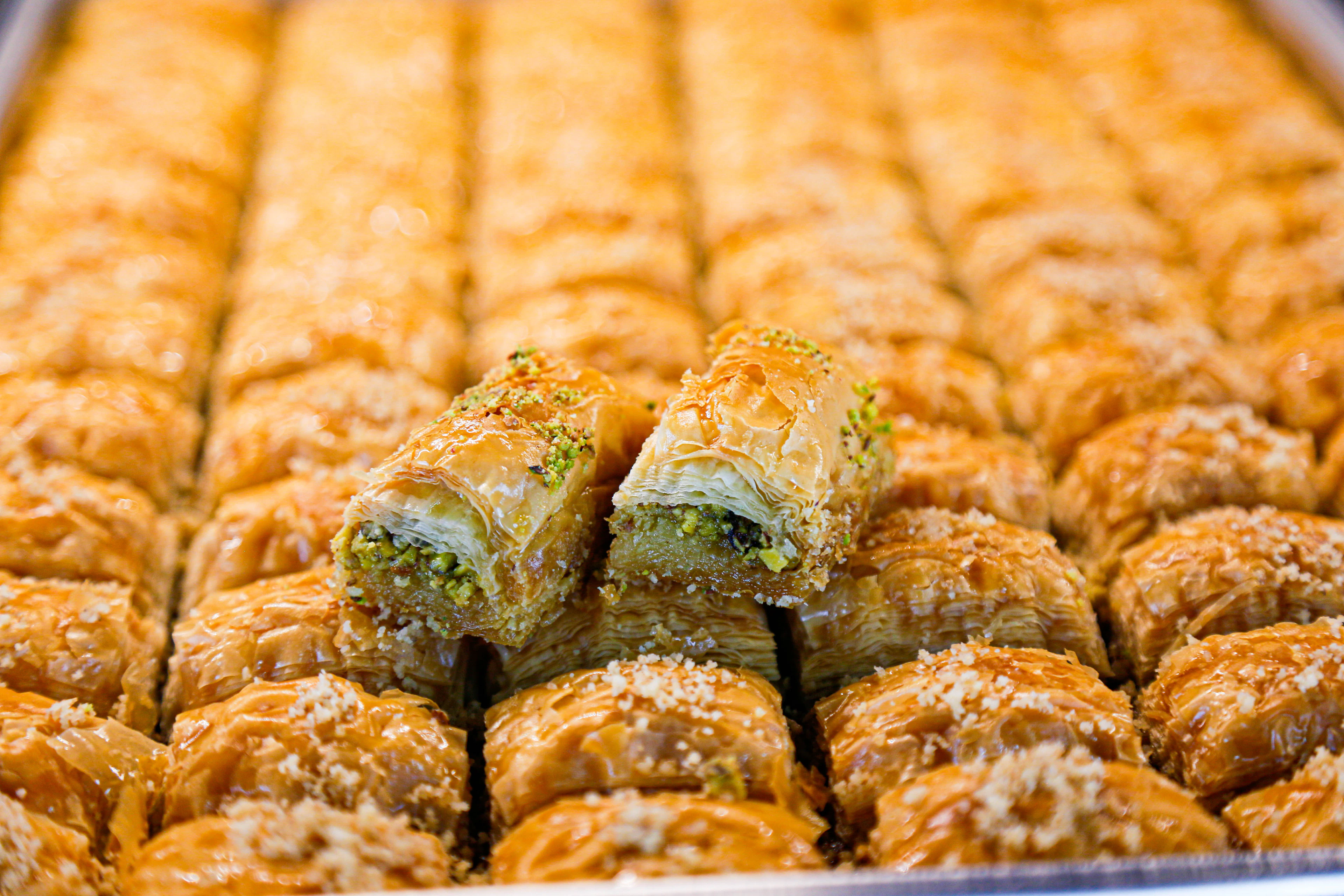 A tray of freshly rolled baklava glistening with syrup
