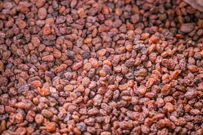 A large pile of dried, small, brown raisins, showcasing their wrinkled texture and varying shades of brown.