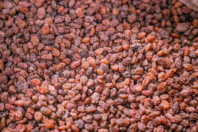 A large pile of dried, small, brown raisins, showcasing their wrinkled texture and varying shades of brown.