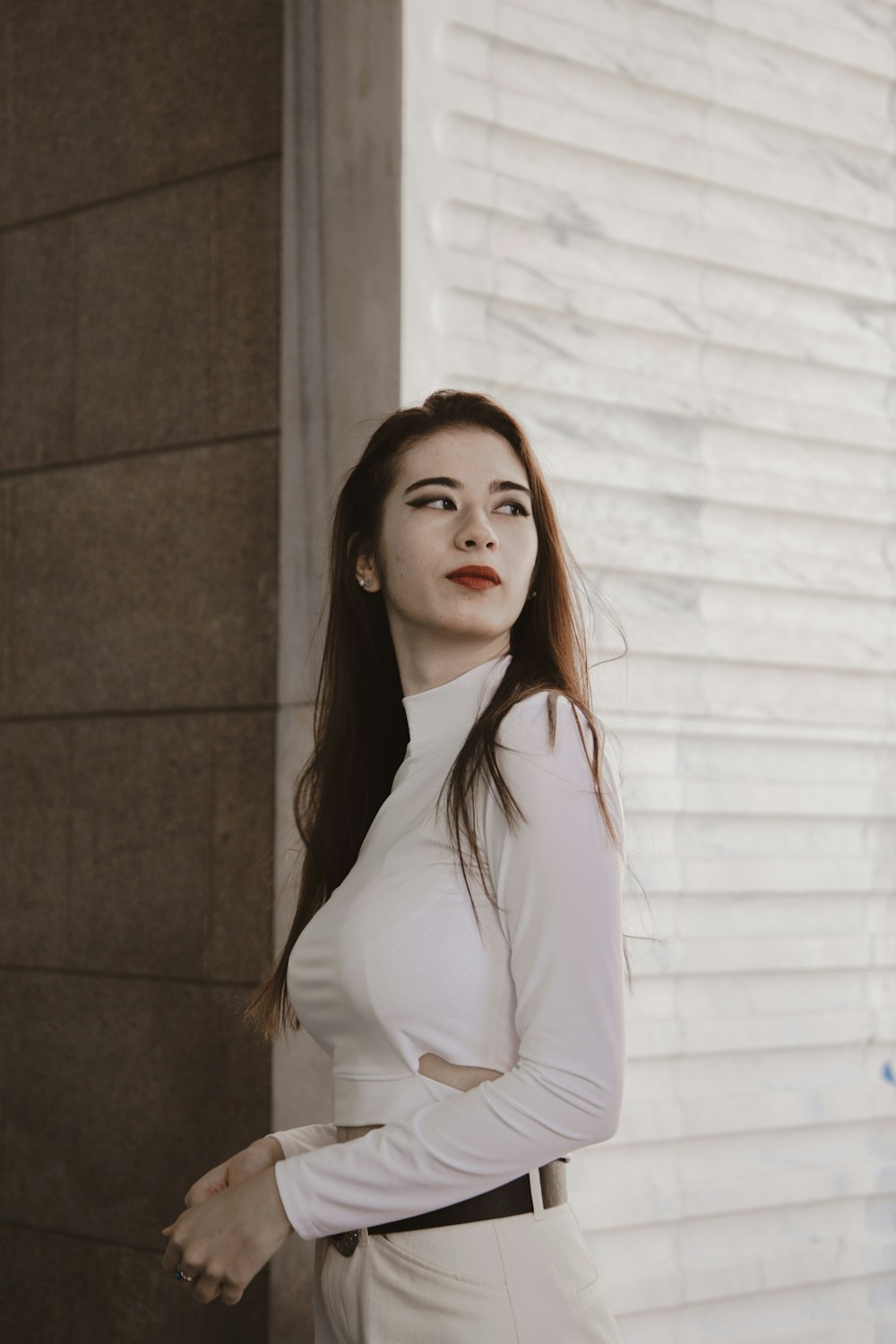 woman in white long sleeve shirt standing beside white wall