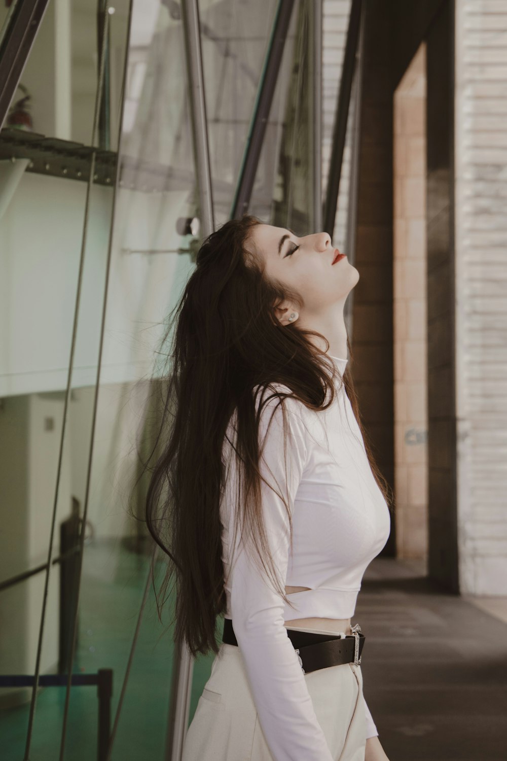 woman in white long sleeve shirt standing near glass wall