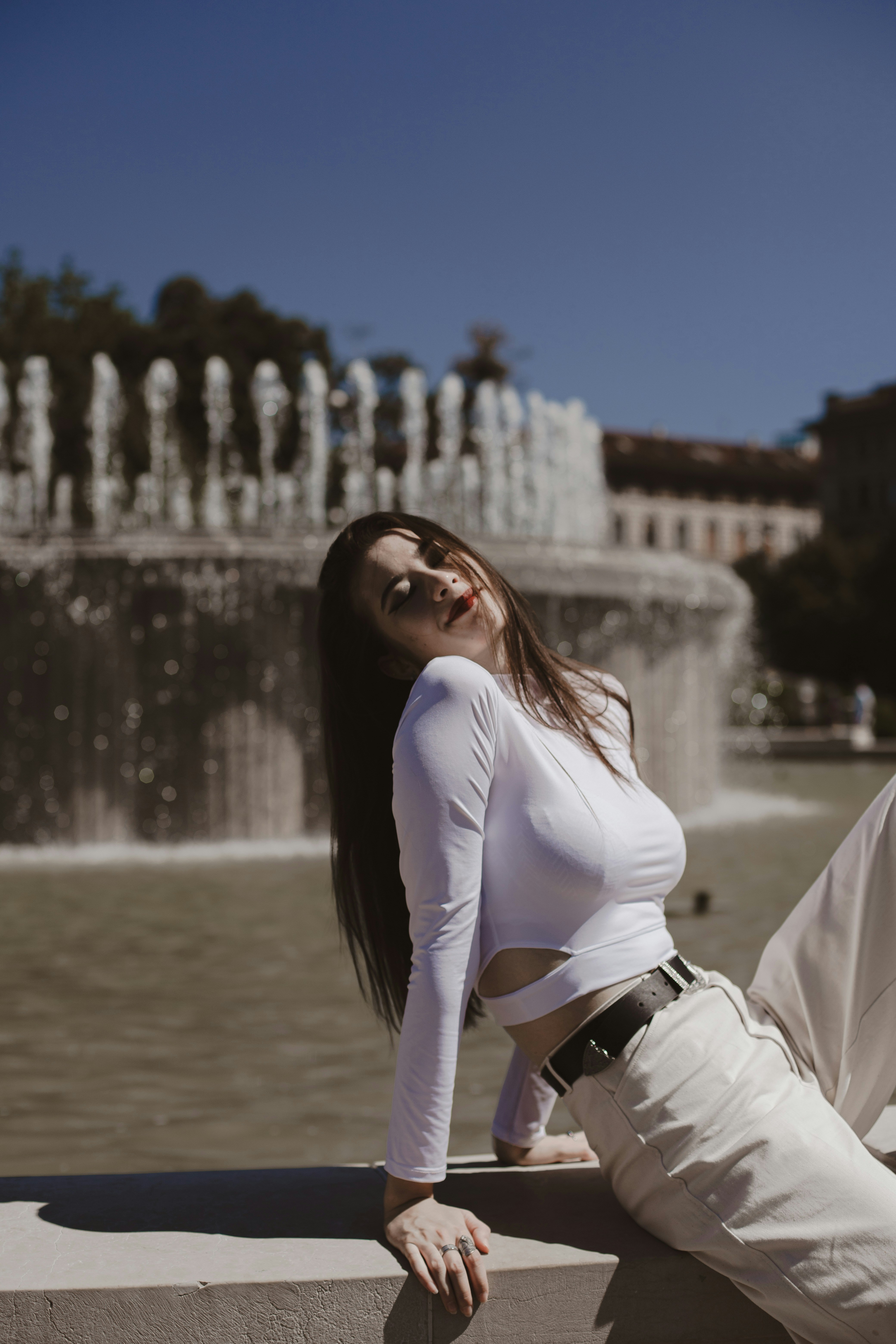 mulher na camisa branca de manga comprida e calças pretas sentadas na doca de madeira marrom durante o dia