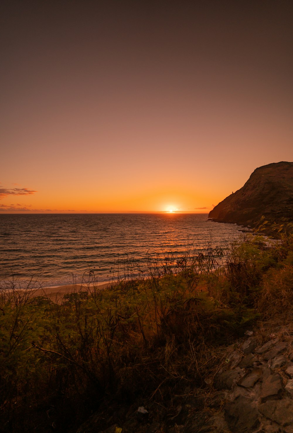 silhouette of mountain near body of water during sunset