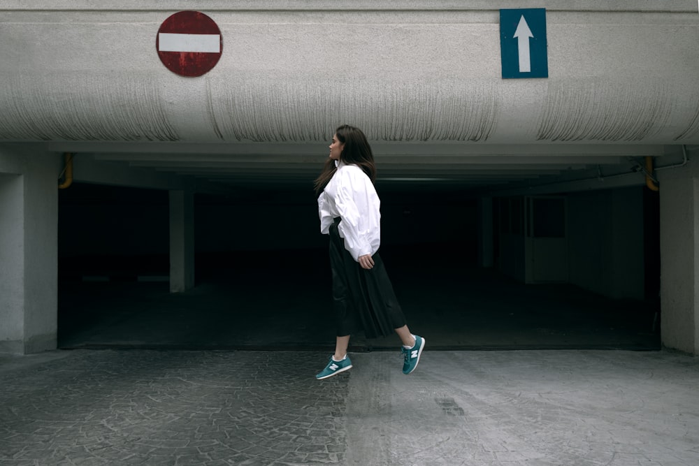 woman in white long sleeve shirt and black skirt standing near white wall