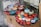 A display of colorful ceramic bowls and decorative items resembling pomegranates are arranged on a raised surface. The objects feature intricate patterns and vibrant colors, including red, blue, orange, and turquoise. They are placed on top of cardboard packaging with labels indicating fragility.