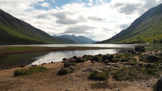 body of water near mountain under white clouds during daytime in Loch Etive United Kingdom