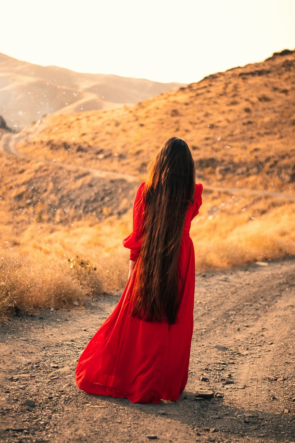 woman in red long sleeve shirt standing on brown field during daytime