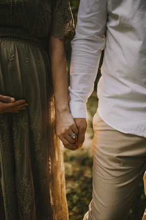 A couple holding hands, showcasing matching embroidered apparel under soft white lighting.