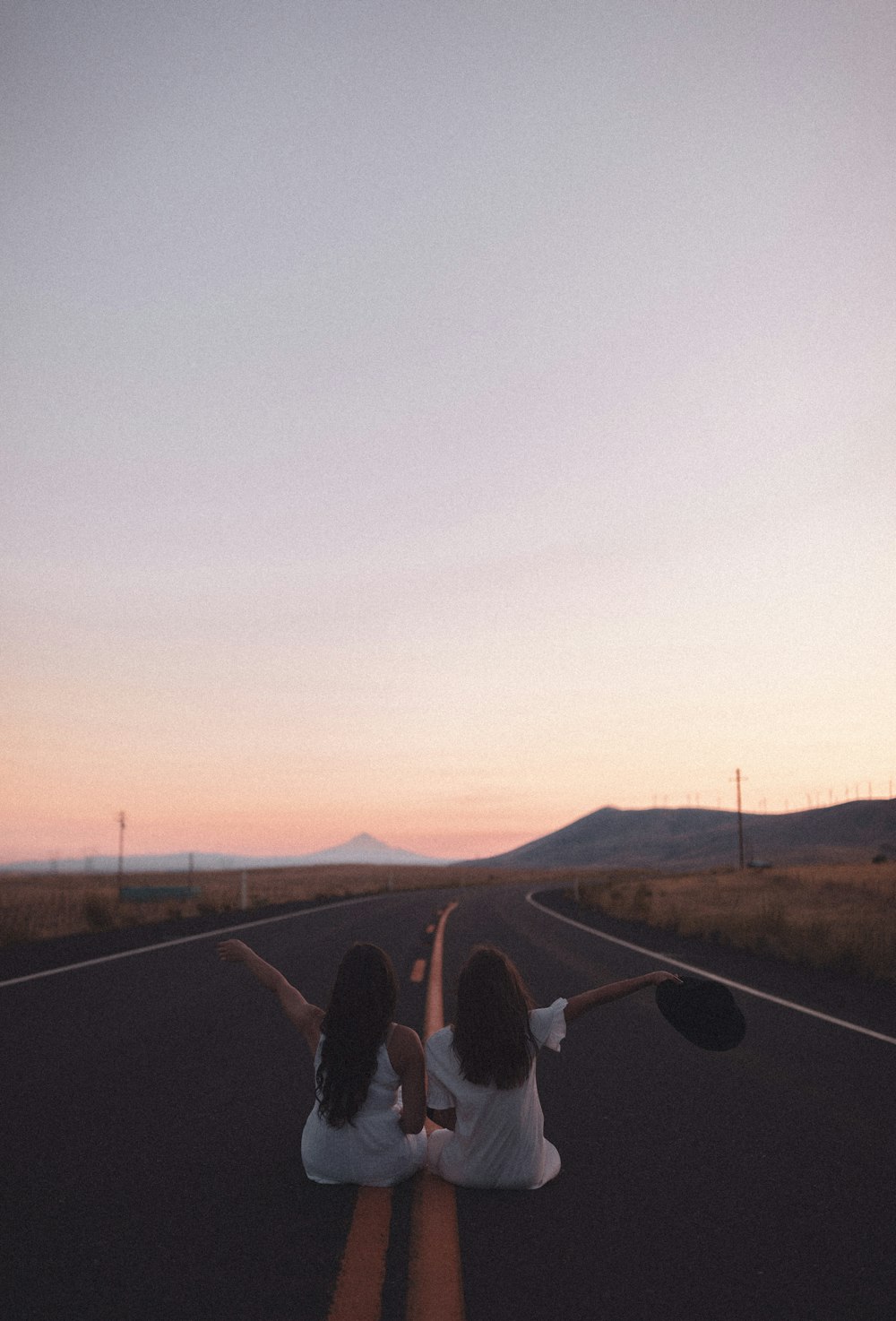 person in black pants and black shoes standing on road during sunset