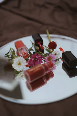 Assorted lip tints arranged artistically with fresh flowers