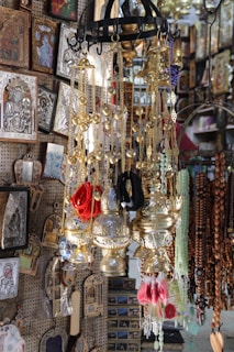 A shop display filled with various religious and decorative items, including hanging brass incense burners, colorful cords, and ornate religious icons with intricate detailing on the walls.