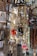 A shop display filled with various religious and decorative items, including hanging brass incense burners, colorful cords, and ornate religious icons with intricate detailing on the walls.
