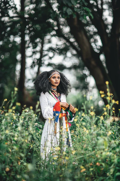 woman in white and blue dress standing on green grass field during daytime