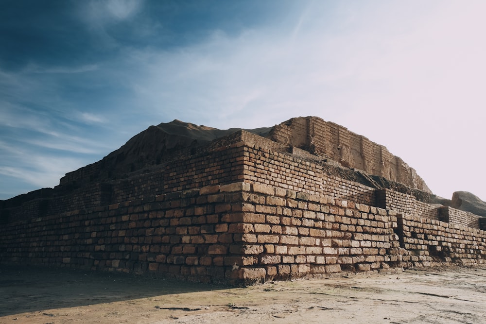 brown brick wall near mountain under blue sky during daytime